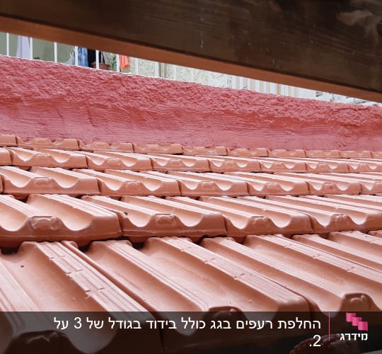 רעפים כתומים על גג עם קיר ורוד ברקע